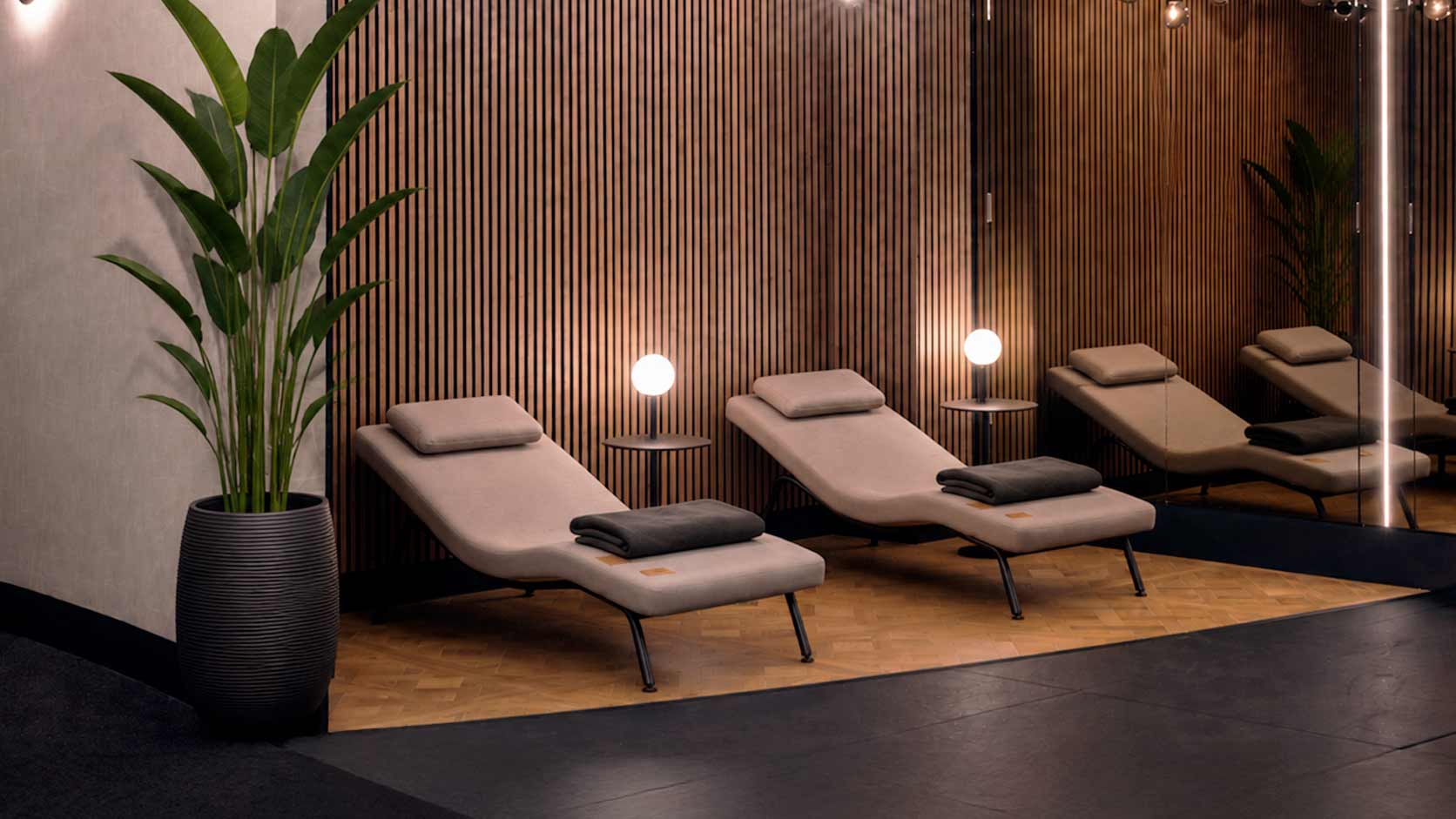 Modern neurosonic chairs in fitness recovery room with wooden walls and potted plants.