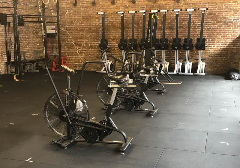 Cardio fitness room with air-bikes, air rowing machines and a rubber gym floor as the surface