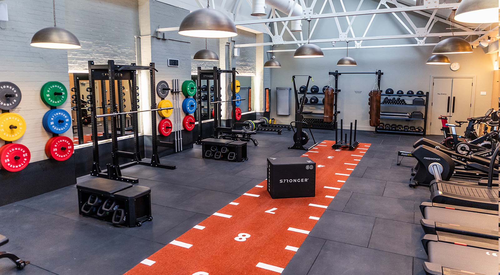 Interior Gym design with free weights area, rubber gym flooring and cardio equipment by Stronger Wellness UK
