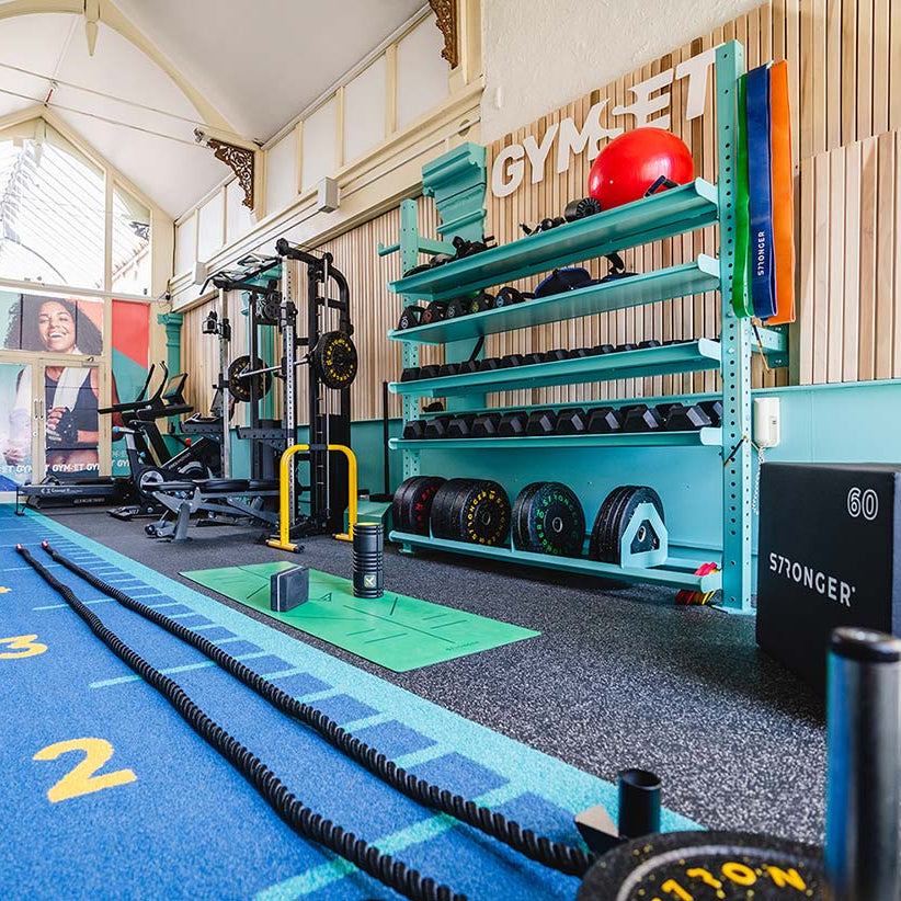 Gym Interior with racks for free weights, half rack, treadmills and blue Sprint Track made from artificial turf.