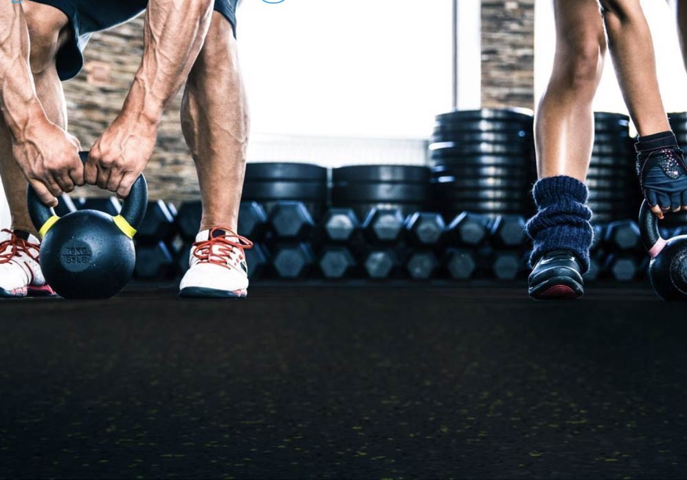 Closeup of Guy training and lifting heavy kettlebell's on a rubber gym floor surface