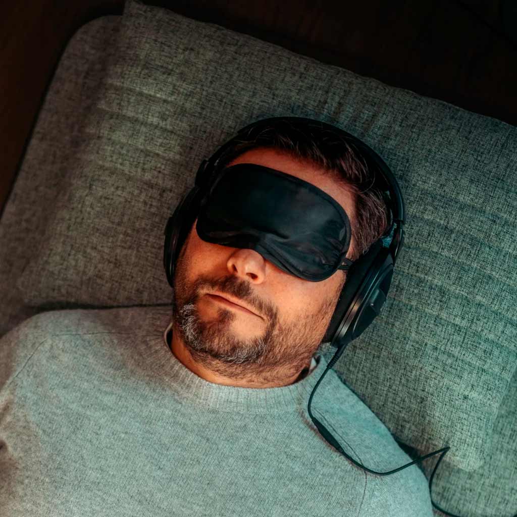 Man wearing a sleep mask and headphones, during recovery with Neurosonic