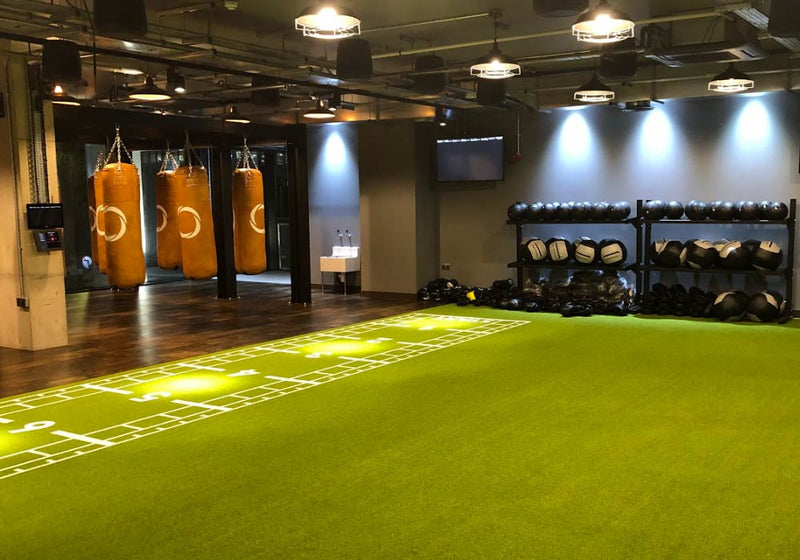 Fitness room with large turf flooring area and cardio area in the back of the workout space 